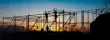Silhouetted construction workers on scaffolding during sunset