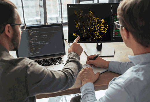Two men looking at a data heatmap of the UK on a computer monitor
